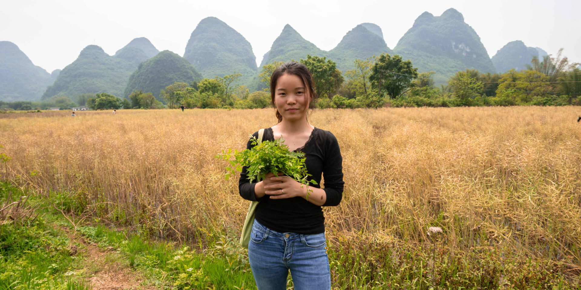 A young woman holds a handful of wild vegetables